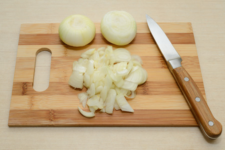 sliced onions and knife on a wooden cutting boardの写真素材