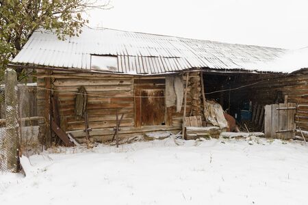 old abandoned wooden shed with a variety of subjects during a snowfallの写真素材
