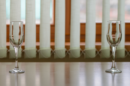 Two glasses on an empty table by the windowの写真素材