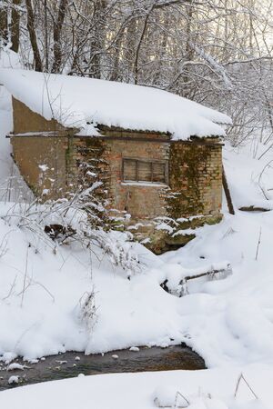 crumbling cabin in a winter snow-covered forestの写真素材