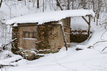 crumbling cabin in a winter snow-covered forestの写真素材