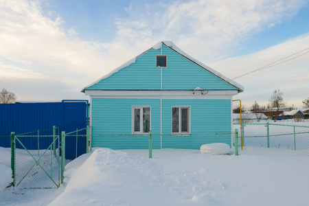 residential one-storey house trimmed with siding snowy winter in the villageの写真素材