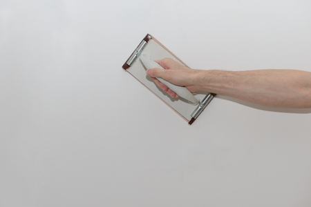 The hand of the worker is leveled by a grater with an emery paper the plastered wallの写真素材