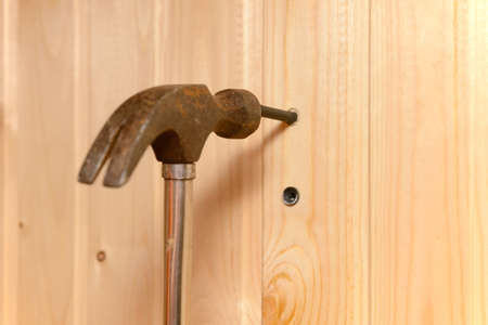 the hammer hits the dowel and hammers it into a hole in the wooden wall