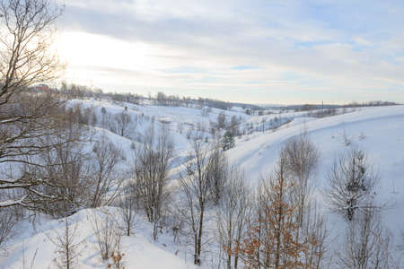 Winter landscape with ravine and hills, trees and housesの写真素材