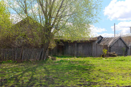An old abandoned rickety wooden house with a gate on a sunny spring dayの写真素材
