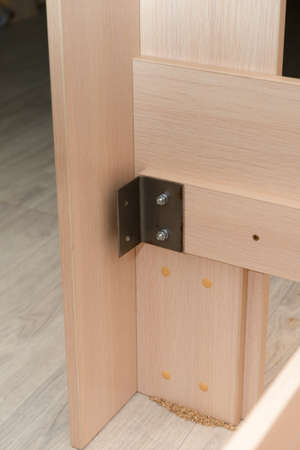 Assembling furniture with a metal corner. Chipboard panels are assembled together.の写真素材