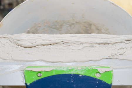 Gypsum plaster on a long steel spatula on a bucketの写真素材