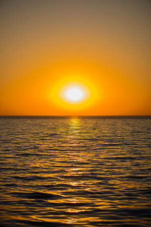 A bright orange sunset over a calm sea