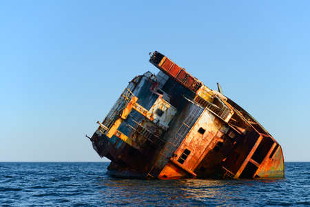 The rusting remains of the hull of a stranded ship in the open seaの写真素材