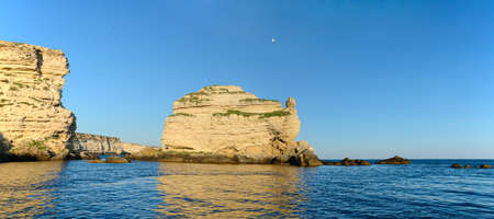 Panorama of the rocky seashore with steep cliffs on a summer evening