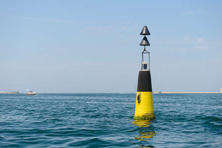 A black and yellow sea buoy bobs on the wavesの写真素材