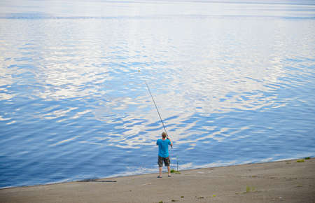 June 14, 2021: A fisherman catches fish with a feeder on the concrete bank of the river. Cheboksary. Russia.のeditorial素材