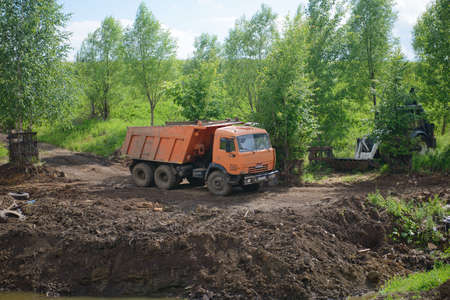 June 19, 2021: Construction equipment, a dump truck, an excavator and a tractor dig the ground for a reservoir. The village of Syatrakasy. Chuvashia. Russia.のeditorial素材