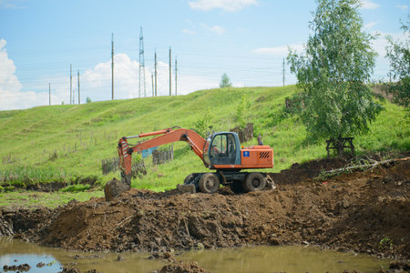 June 19, 2021: Construction equipment, a dump truck, an excavator and a tractor dig the ground for a reservoir. The village of Syatrakasy. Chuvashia. Russia.のeditorial素材