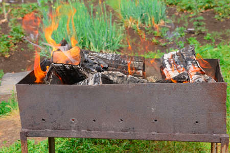 Burning logs in an old metal barbecue in the gardenの写真素材