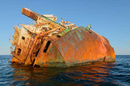 The rusty frame of a stranded naval ship in the middle of the seaの写真素材