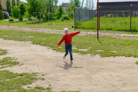 A smiling child in red clothes runs with his arms outstretched in the courtyard of a private houseの写真素材
