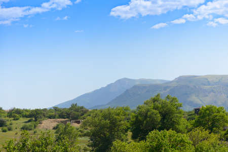 Old abandoned buildings against the backdrop of mountains on a summer dayの写真素材