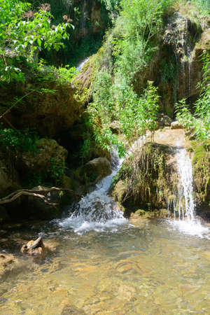 Winding waterfall with green mountain slopesの写真素材