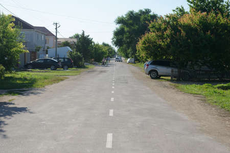 July 9, 2021: A street with cars and houses of the resort village of Mezhvodnoye on the Black Sea coast. The village of Mezhvodnoye. Russia.のeditorial素材