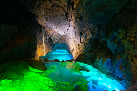 Underground river in a cave illuminated by colored lampsの写真素材