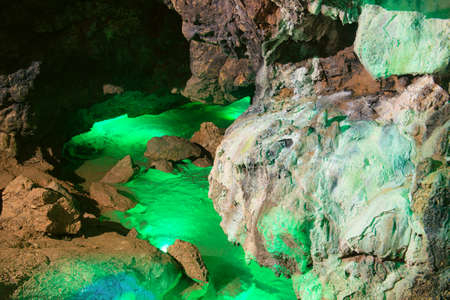 Underground river in a cave illuminated by colored lampsの写真素材