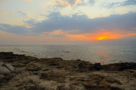 Evening seascape with rocky shore and setting sunの写真素材