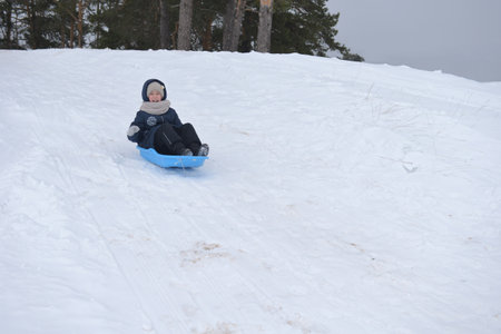 The girl slides down the snow slide and smilesの写真素材
