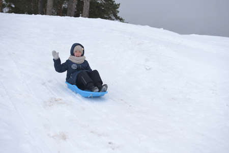 The girl slides down the snow slide and smilesの写真素材