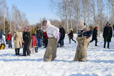 March 13, 2021: Girls compete jumping in bags on a winter day. Cheboksary. Russia.のeditorial素材