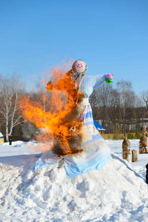 The effigy of winter on Shrovetide burns with a bright flame among snowdriftsの写真素材