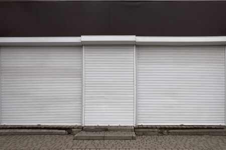 An old, abandoned shop with metal curtains closed.