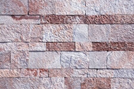 Background, texture laying of natural stone in a light red hue.