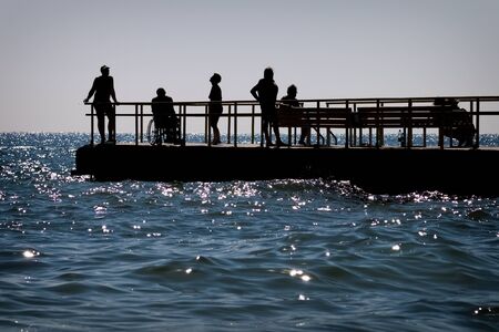 Silhouettes of elderly and disabled vacationers at sea.の写真素材
