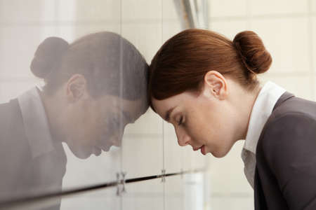 Businesswoman in fatigue leaned her head on wall の写真素材