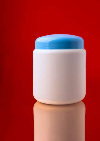 Low wide cosmetics bottle with reflection on red の写真素材