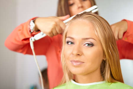 Hair salon. Women`s haircut. Use of straightener.の写真素材
