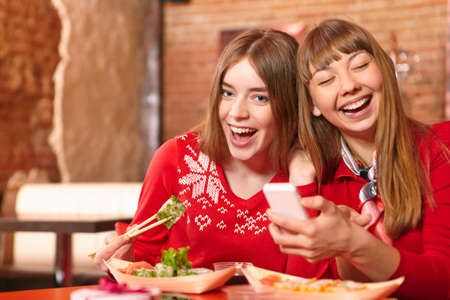 Beautiful girls eat sushi rolls at sushi bar.の写真素材