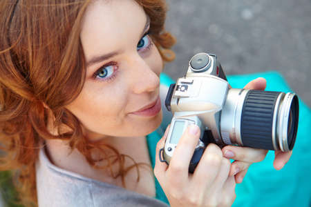 Young woman uses digital slr photocamera.の写真素材