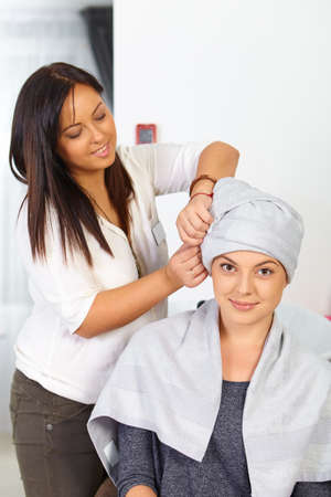Young woman with towel on head in hair salon.の写真素材