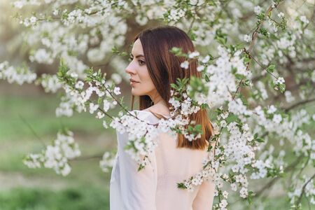 Amazing young woman posing in Blooming tree orchard at springの写真素材