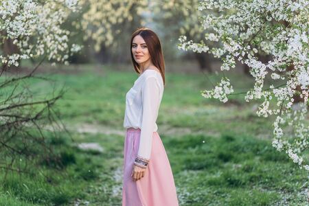 Amazing young woman posing in Blooming tree orchard at springの写真素材