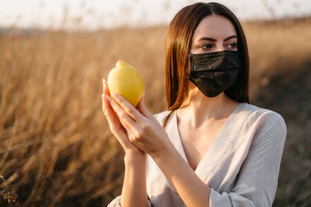Portrait of woman in mask with lemonの写真素材