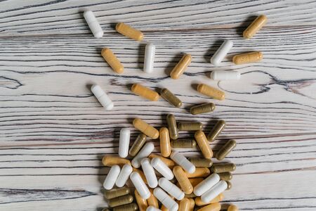 sprinkled pills and dietary supplements on a wooden background, vitamins and omega3 for immunityの写真素材