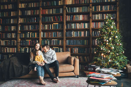 Happy family at home in cozy living room with a decorated festive Christmas treeの写真素材