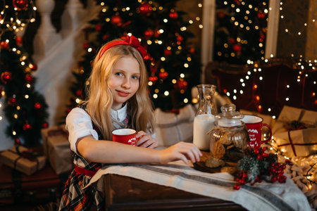 Good New Year spirit. Little blonde girl sitting near a Christmas tree with a gift waiting for Santa. High quality photoの写真素材