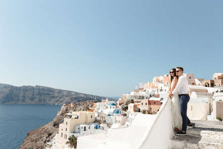 Happy couple hugging and laughing together with a view of Santorini. High quality photoの写真素材