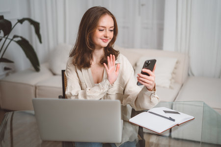 Happy young business woman employee, hr manager having remote online work hybrid meeting or distance job interview waving hand looking at laptop during virtual video conference call in office. Highの写真素材