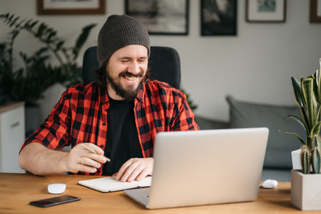 Friendly confident young adult caucasian broker, freelancer or manager in formal clothes and glasses using laptop, talk to colleagues or clients on conference call, greeting hand gesture, smilingの写真素材